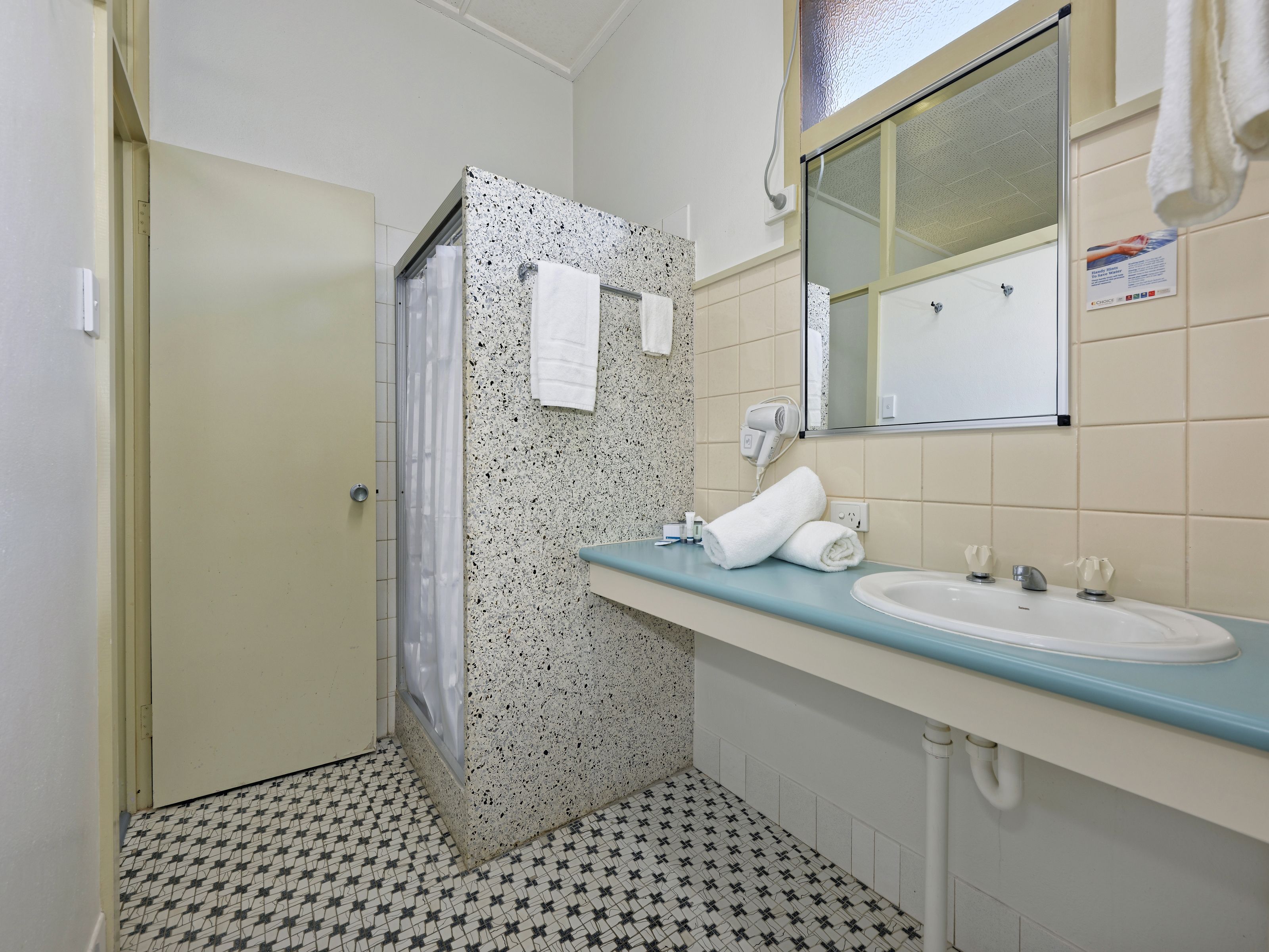 A bathroom with a shower, a sink, and a mirror.