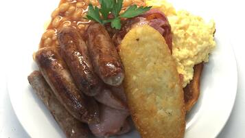 Ein Teller mit Wurst, Bohnen, Rührei und einer Bratkartoffel.