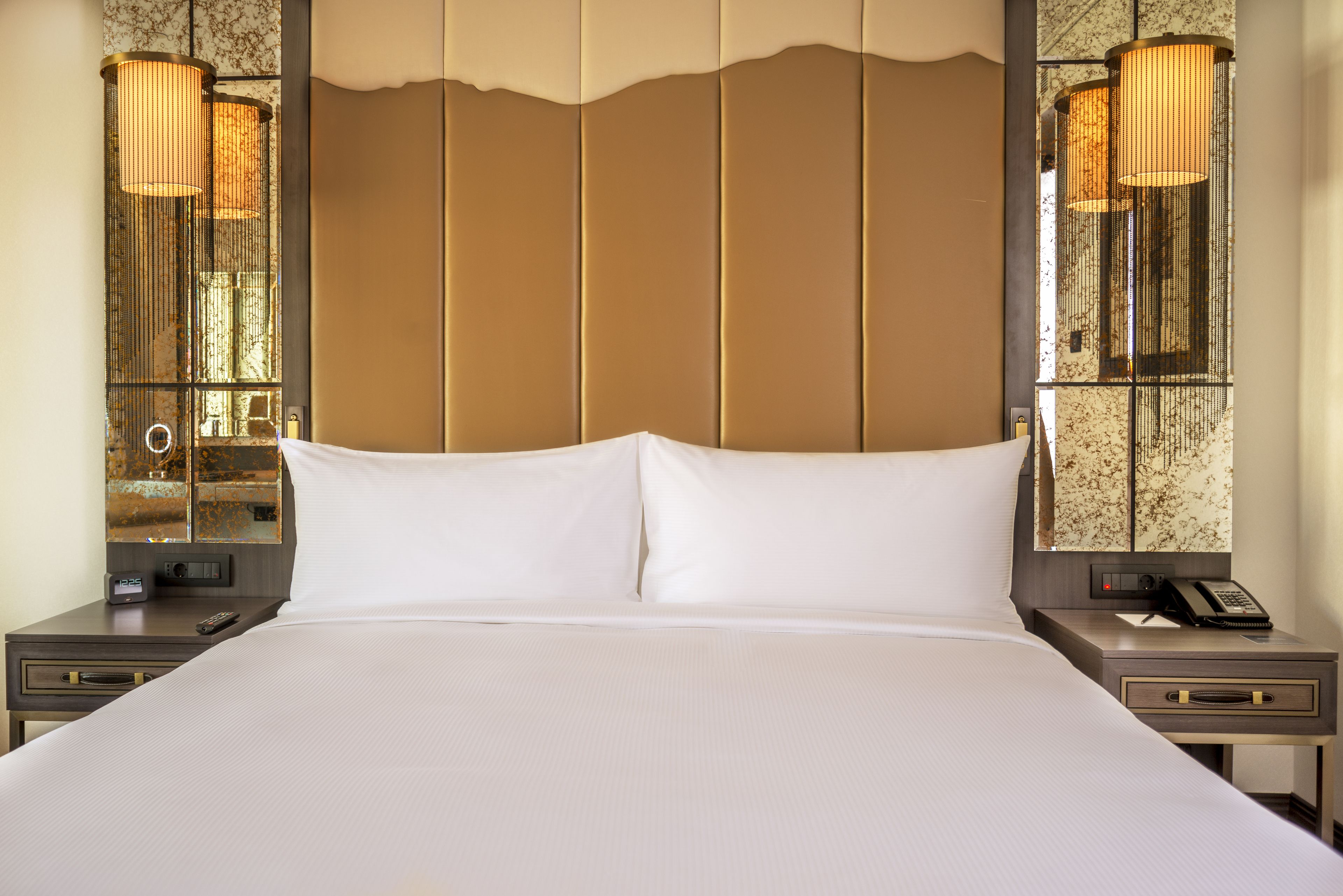 A large bed with white linens, a wooden headboard, and two bedside tables with lamps.
