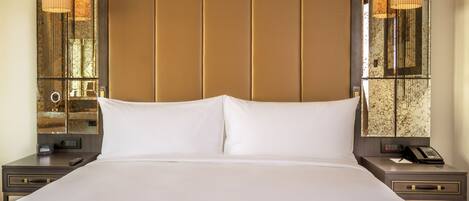 A large bed with white linens, a wooden headboard, and two bedside tables with lamps.