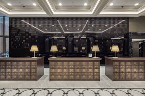 A lobby with a reception desk, multiple seating areas, and a wall decorated with numerous keys. - Hilton Podgorica Crna Gora (Podgorica)