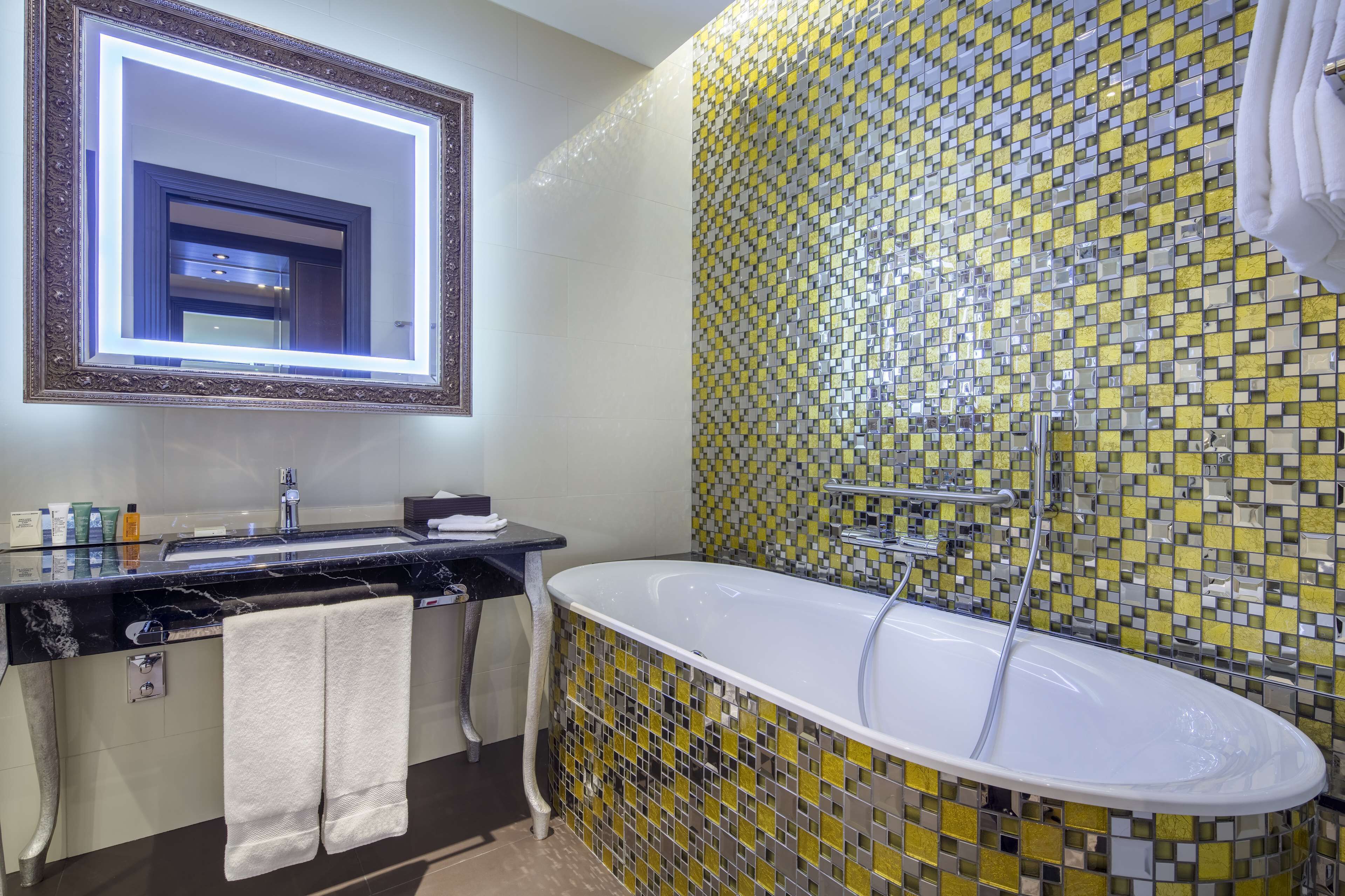 Un baño con un espejo grande, una bañera y un muro con azulejos.