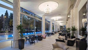 A spacious outdoor seating area with modern furniture, large windows, and a fountain.