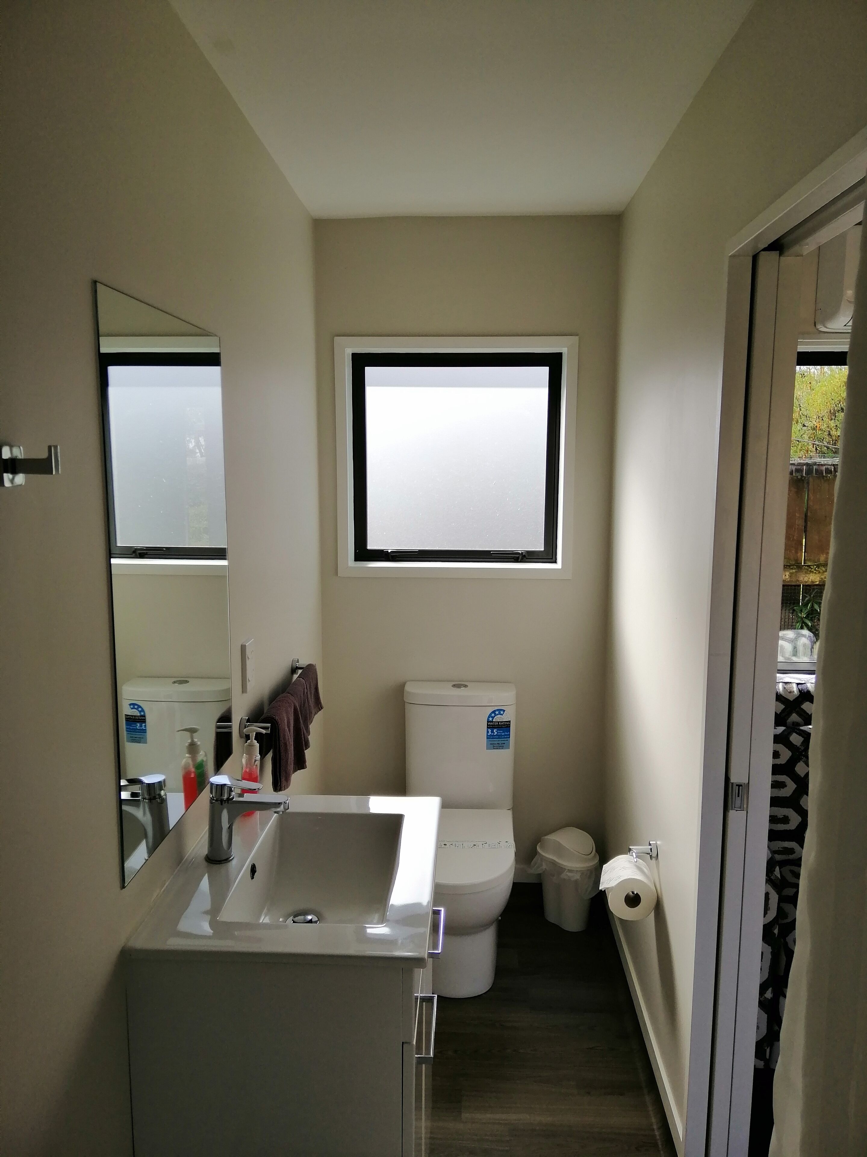 A compact bathroom with a toilet, a sink, and a window.