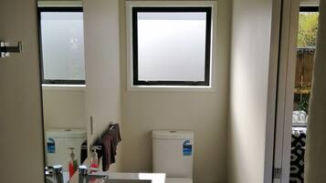 A compact bathroom with a toilet, a sink, and a window.