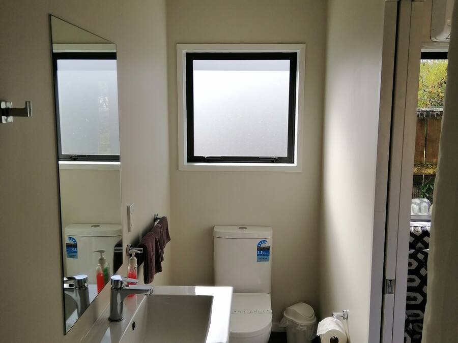 A compact bathroom with a toilet, a sink, and a window.