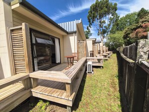 A wooden deck with outdoor seating and a sliding glass door leading to a covered patio area.