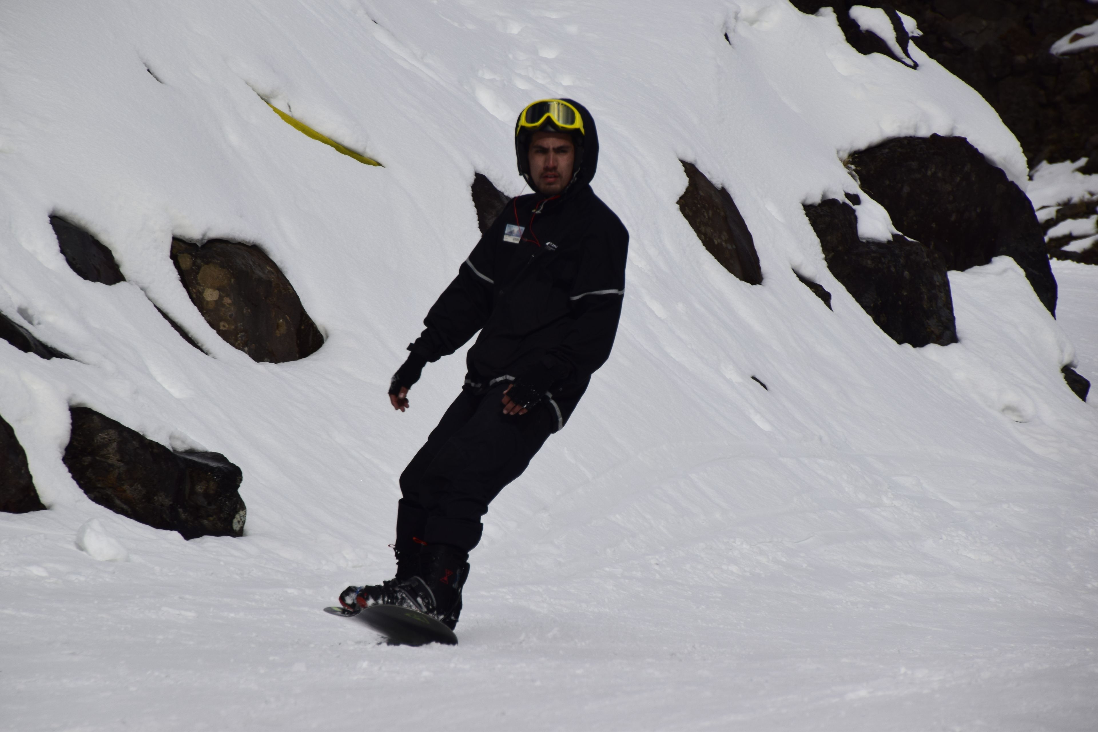 A snowboarder on a snowy slope with rocks.