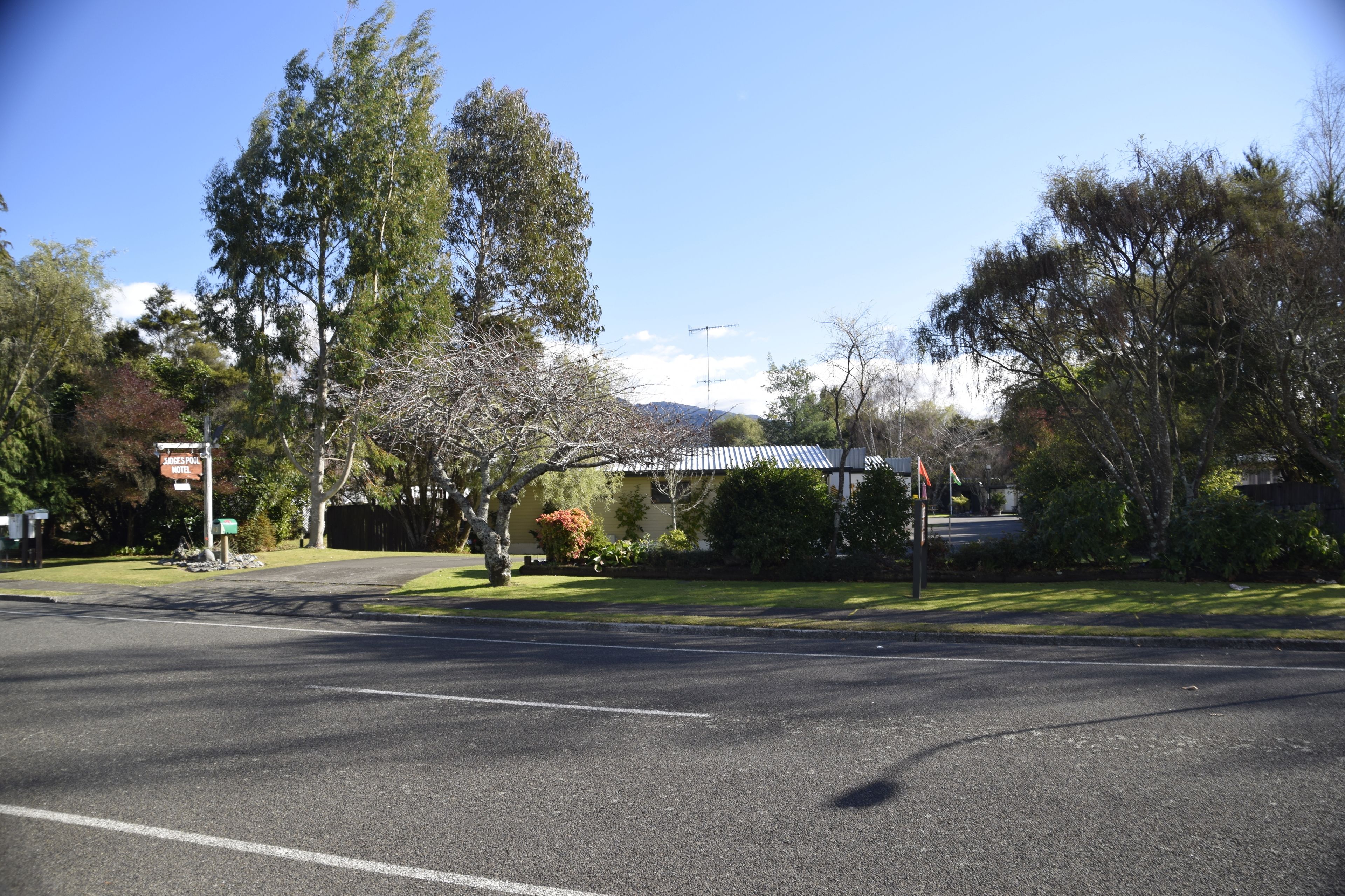 A road intersection with a motel sign, trees, and a building with a metal roof.