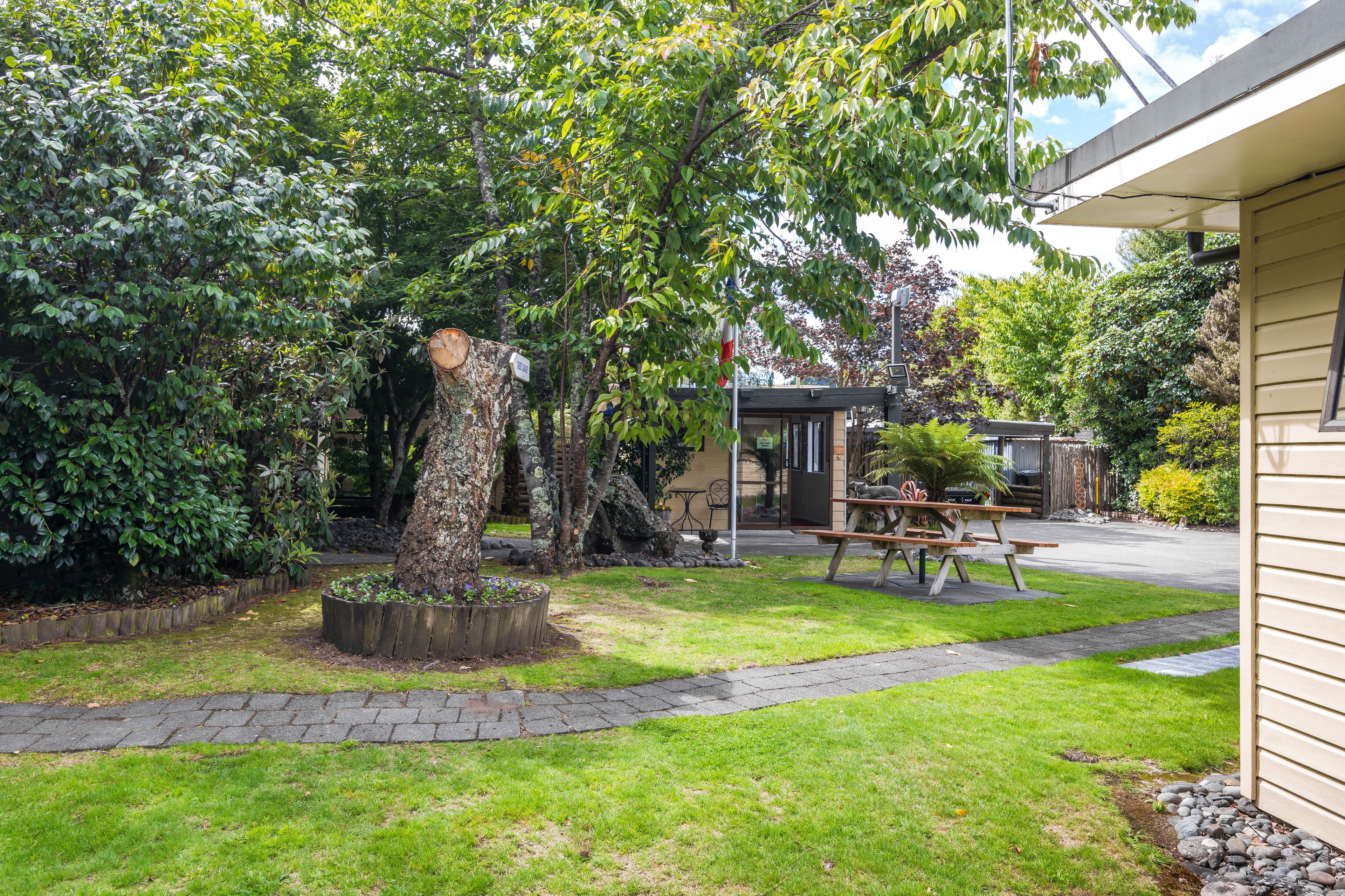 A well-maintained garden with a picnic table, a stone pathway, and a small building with a window.