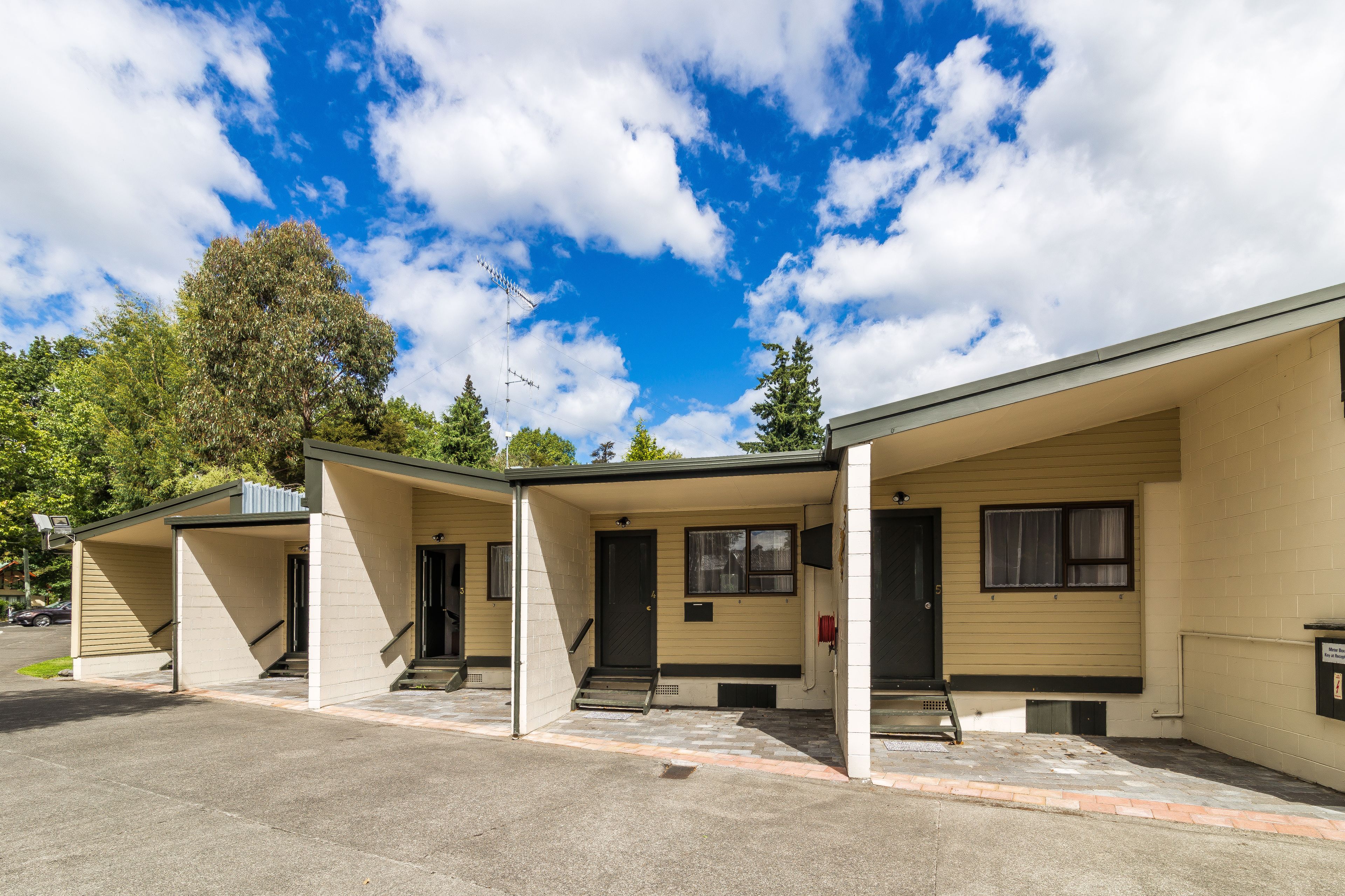 A row of single-story motel buildings with individual entrances and a clear sky.