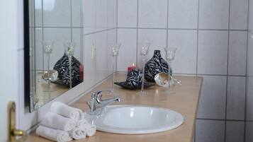 Ein Badezimmer mit einem weißen Waschbecken, einem Spiegel und Handtüchern.