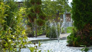 A garden with a water feature, surrounded by white pebbles and various plants. - Landhotel Zerlaut (Kisslegg)