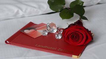 A red book titled "Landhotel Zertaft" with a red rose and clear crystal decorations on a white fabric background.