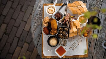 A wooden table with a variety of food items including bread, olives, and dips, placed on a sign that reads "HOTEL IN SALLAND".