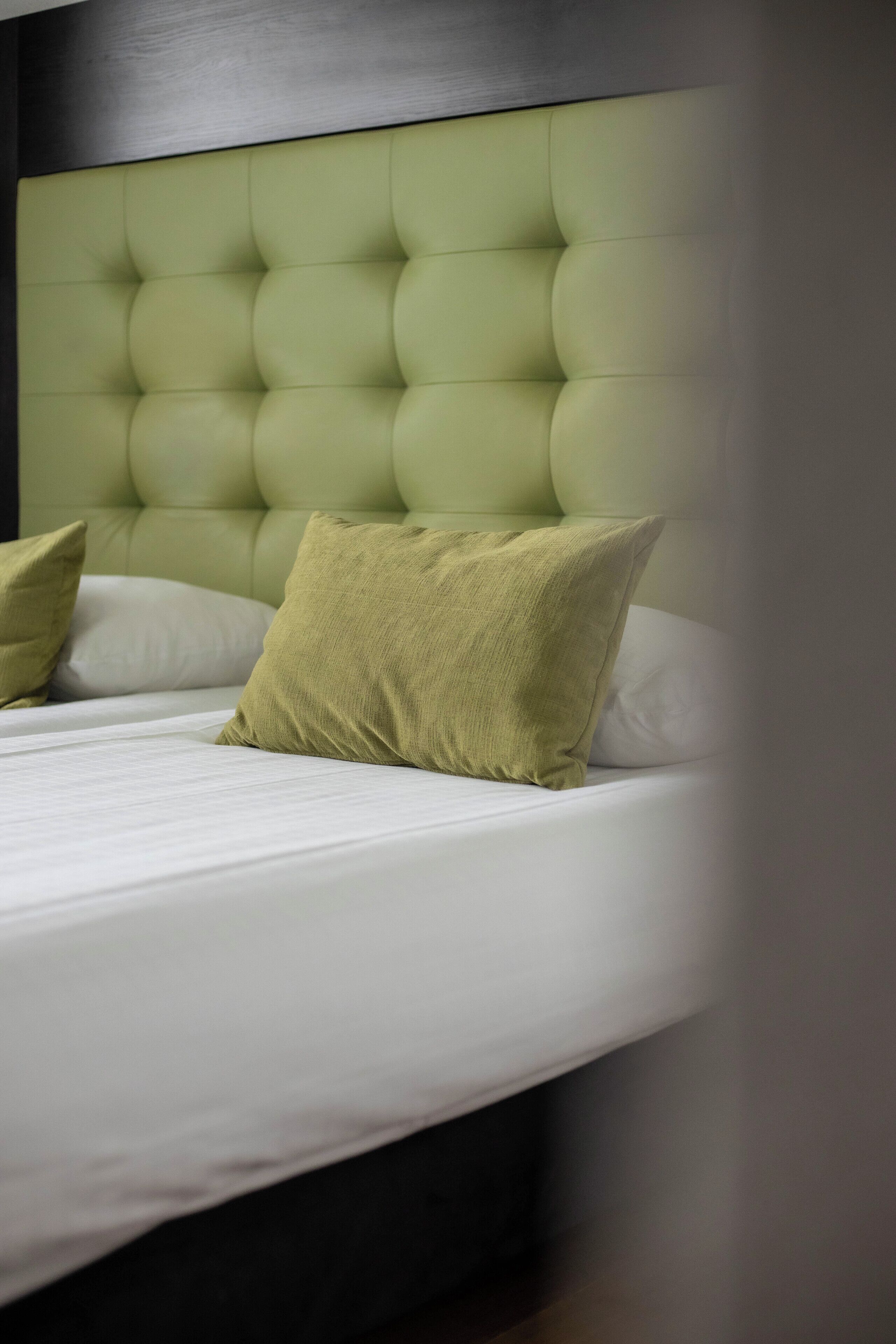 A bed with a tufted headboard, two pillows, and a white mattress.