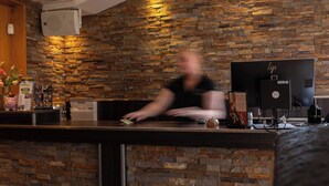 A reception area with a stone wall, a reception desk, and a computer monitor. - Hotel Inn Salland (Raalte)
