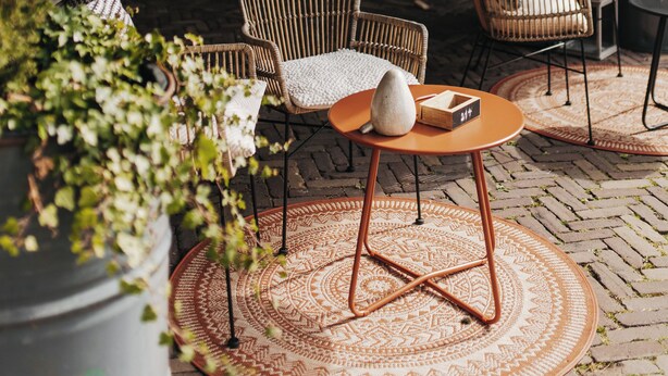 An outdoor seating area with wicker chairs, a round table, and a patterned rug. - Hotel Inn Salland (Raalte)