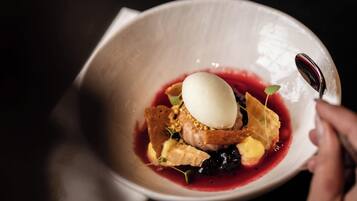 A bowl of dessert with a scoop of ice cream and berries.