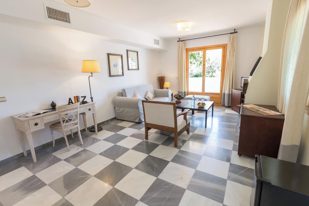 A living room with a checkered floor, a sofa, a desk, and a dining table.