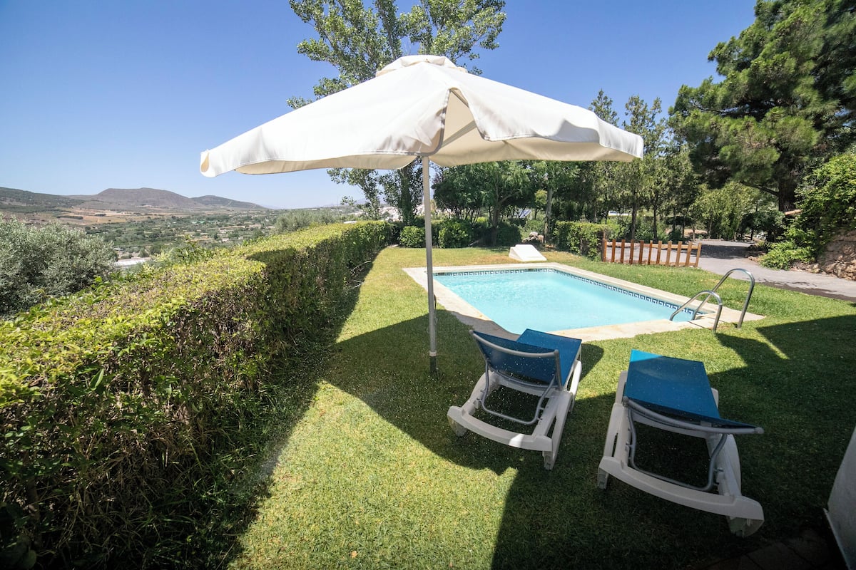 A swimming pool with two lounge chairs and a large umbrella.