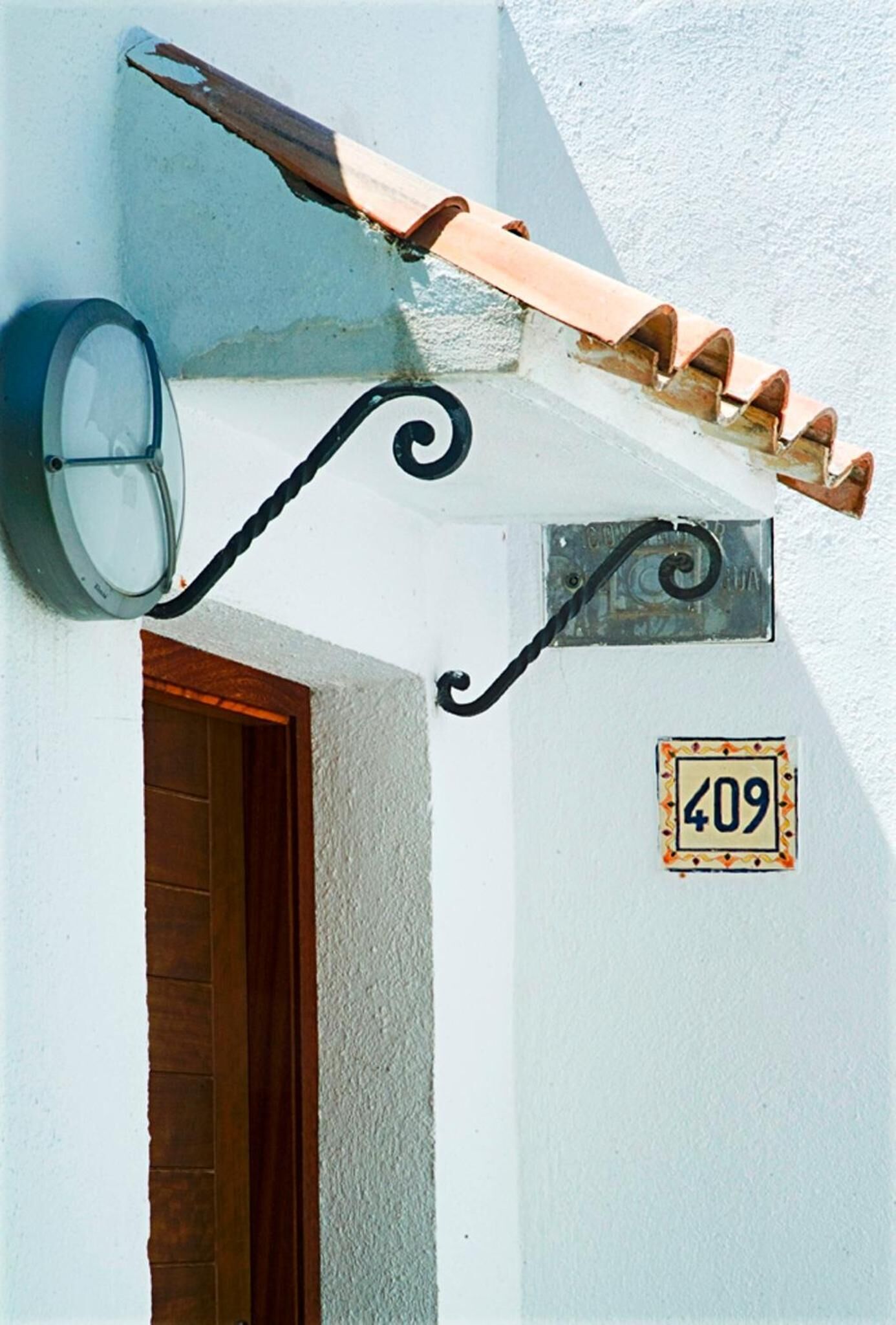 Una esquina de edificio con una placa con el número '409', una puerta y un aplique de pared.