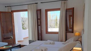 A spacious bedroom with a large bed, two windows, a bedside table with a lamp, and a view of the outdoors. - Villa Turística de Laujar de Andarax (Laujar de Andarax)