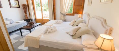 Habitación de hotel con una cama grande, dos mesitas de noche, una mesita de noche con lámpara y vistas al exterior a través de las ventanas.