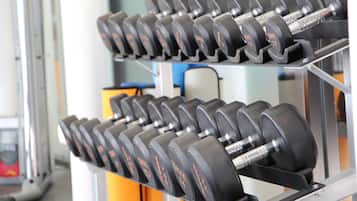 A rack of black dumbbells with red markings, likely indicating weight, in a gym setting.