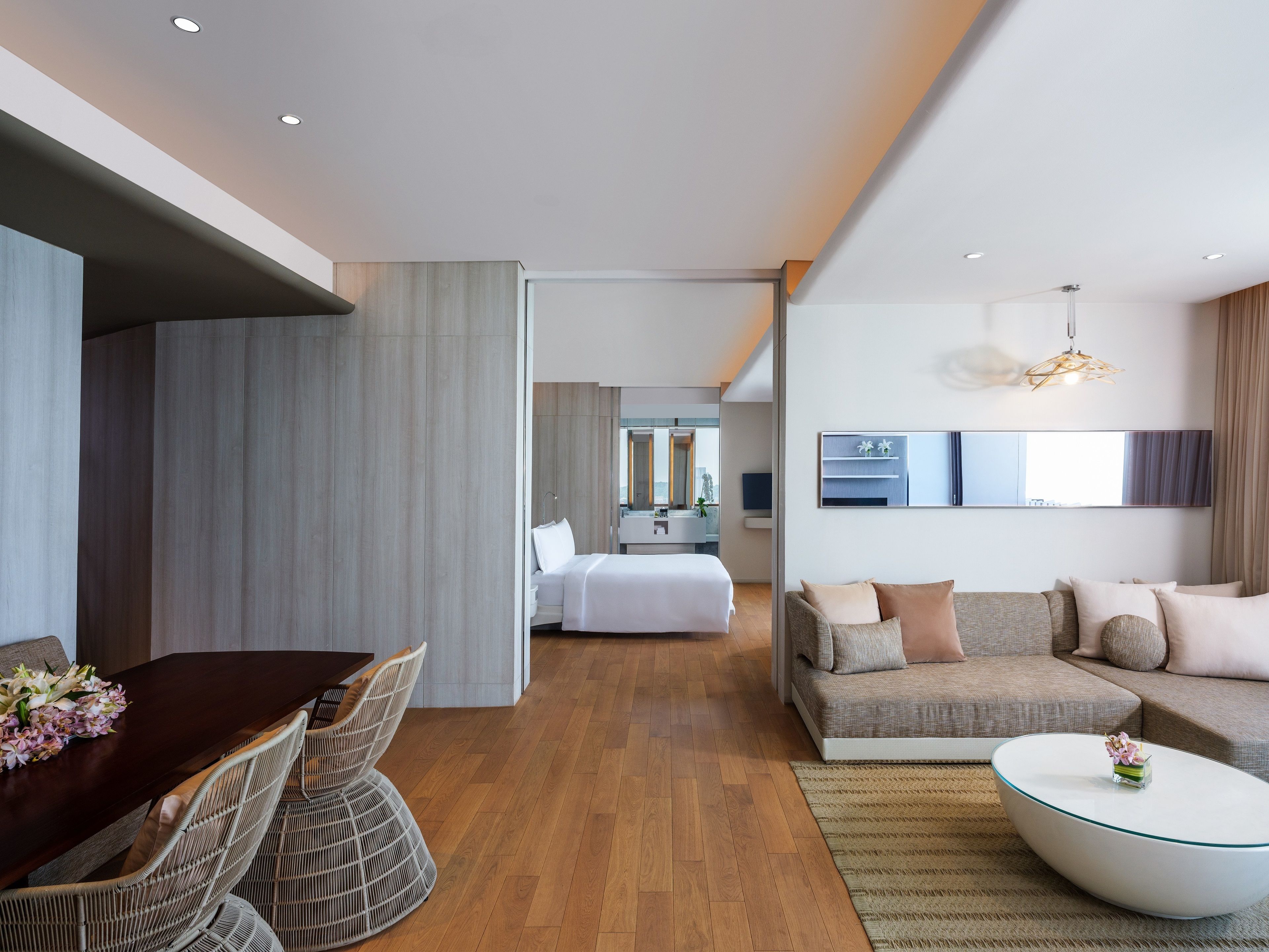 Una habitación de hotel moderna con comedor, sala de estar y dormitorio.