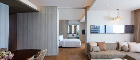 Una habitación de hotel moderna con comedor, sala de estar y dormitorio.
