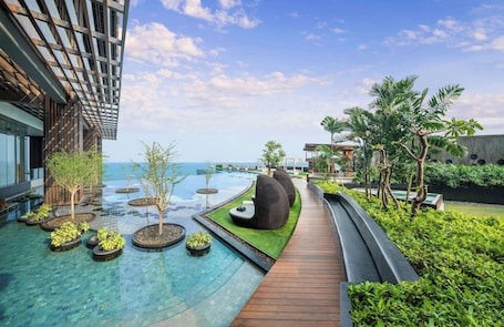 A modern resort with a swimming pool, wooden deck, and lush greenery.
