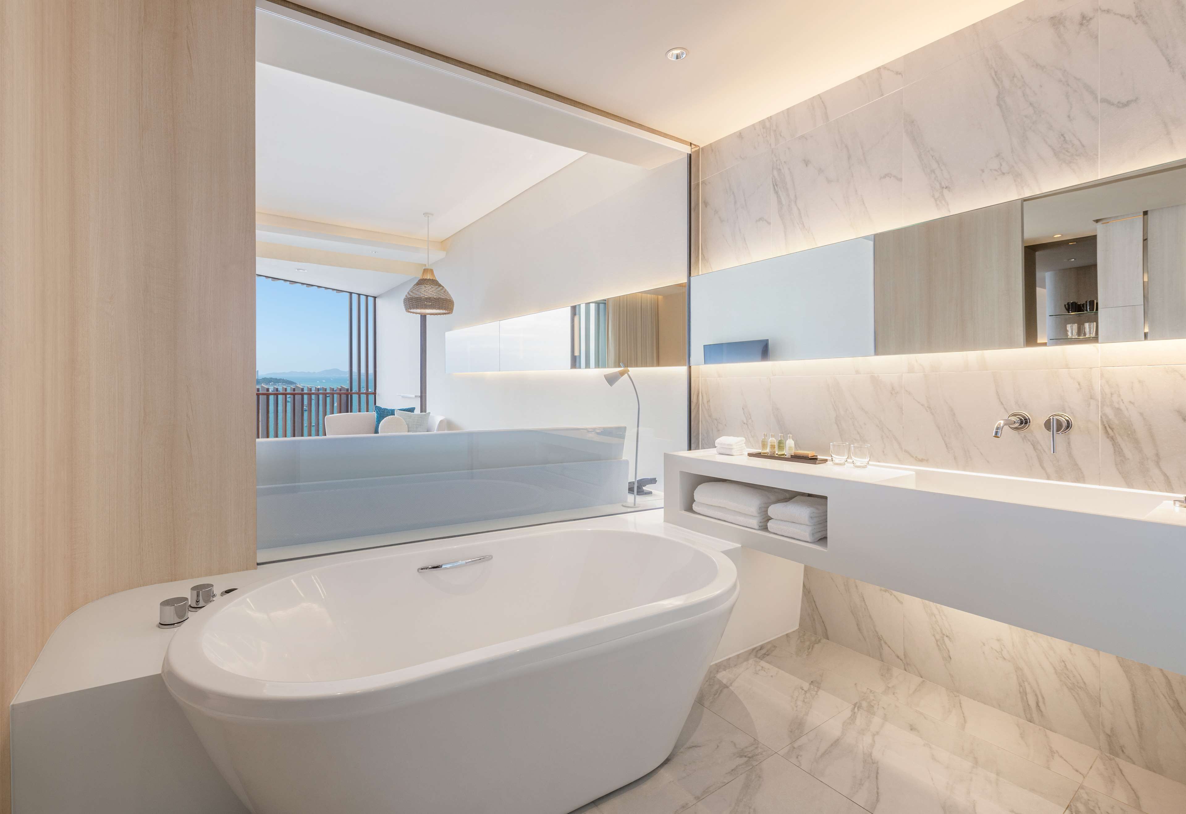 A modern bathroom with a large bathtub, a built-in vanity, and a large mirror.
