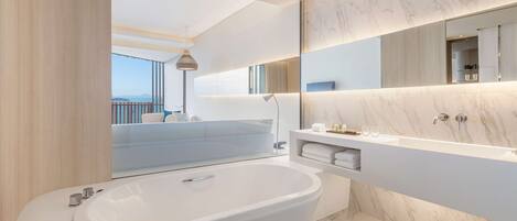 A modern bathroom with a large bathtub, a built-in vanity, and a large mirror.