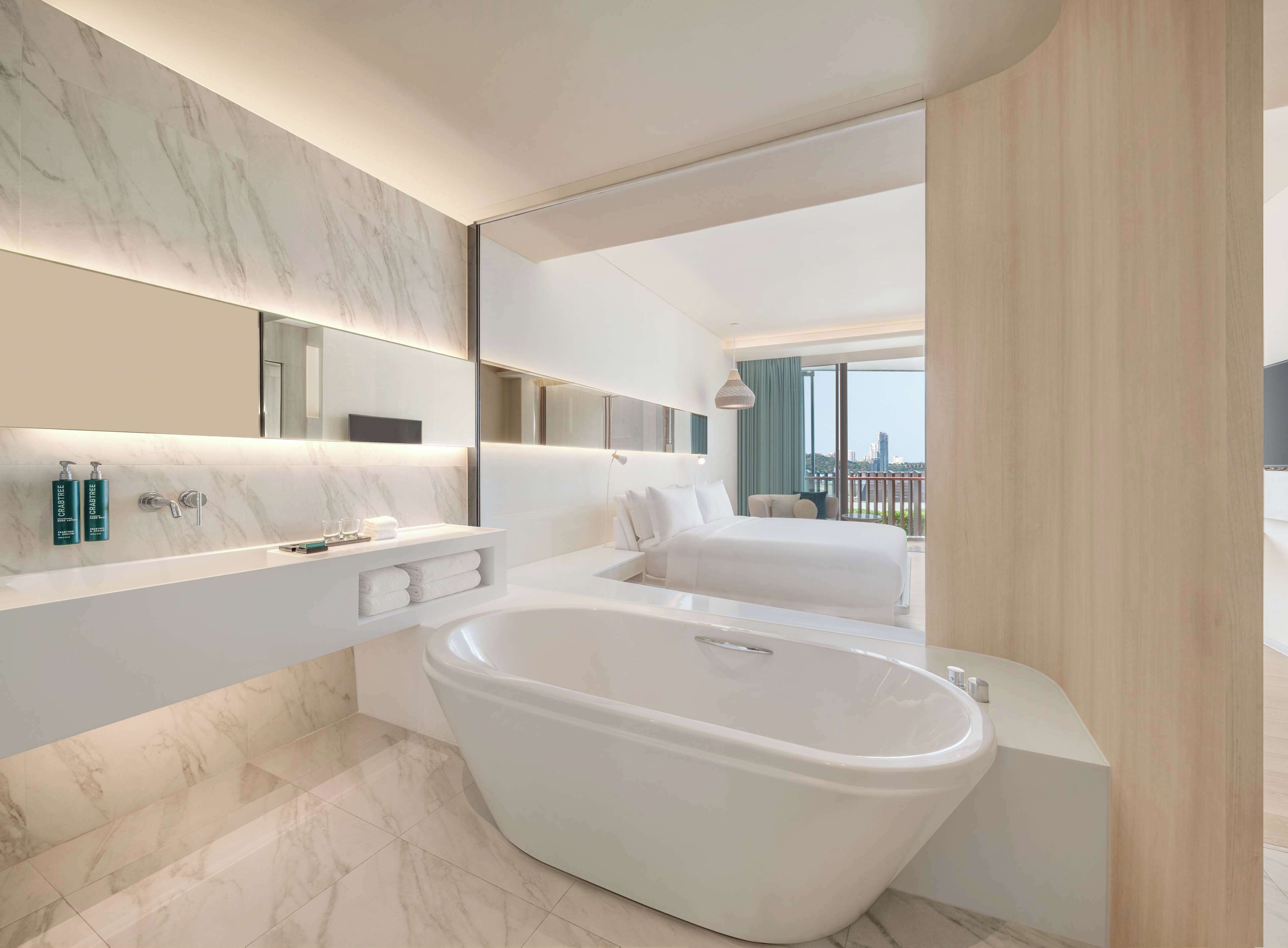 Un baño moderno con una bañera grande, un tocador con espejo y vistas a la ciudad.