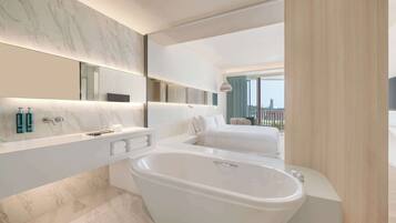 Un baño moderno con una bañera grande, un tocador con espejo y vistas a la ciudad.
