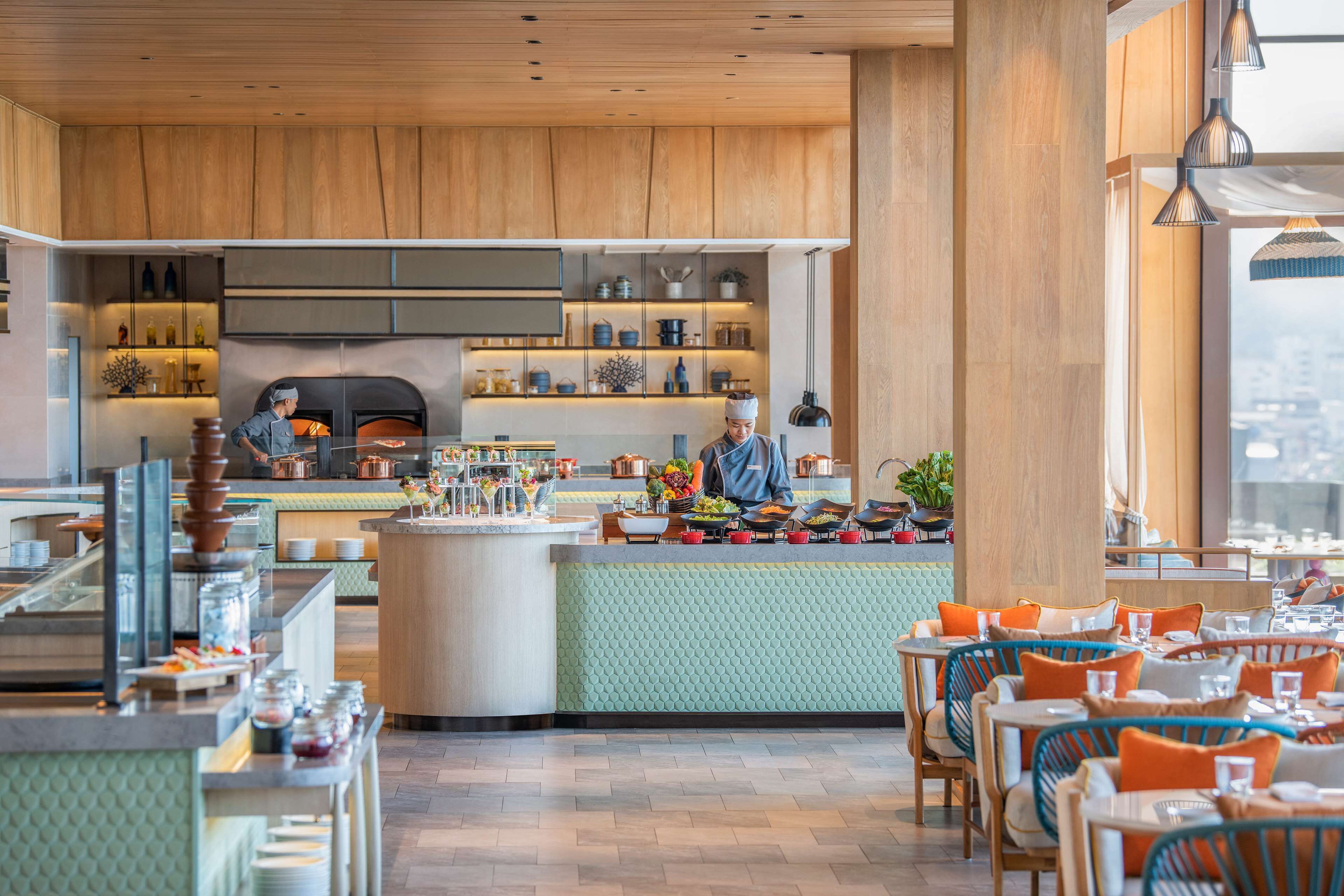 Un restaurante moderno con detalles de madera, una zona de bar central y asientos dispuestos alrededor.