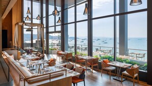 A spacious dining area with large windows offering a view of the sea and boats. - Hilton Pattaya (Pattaya)