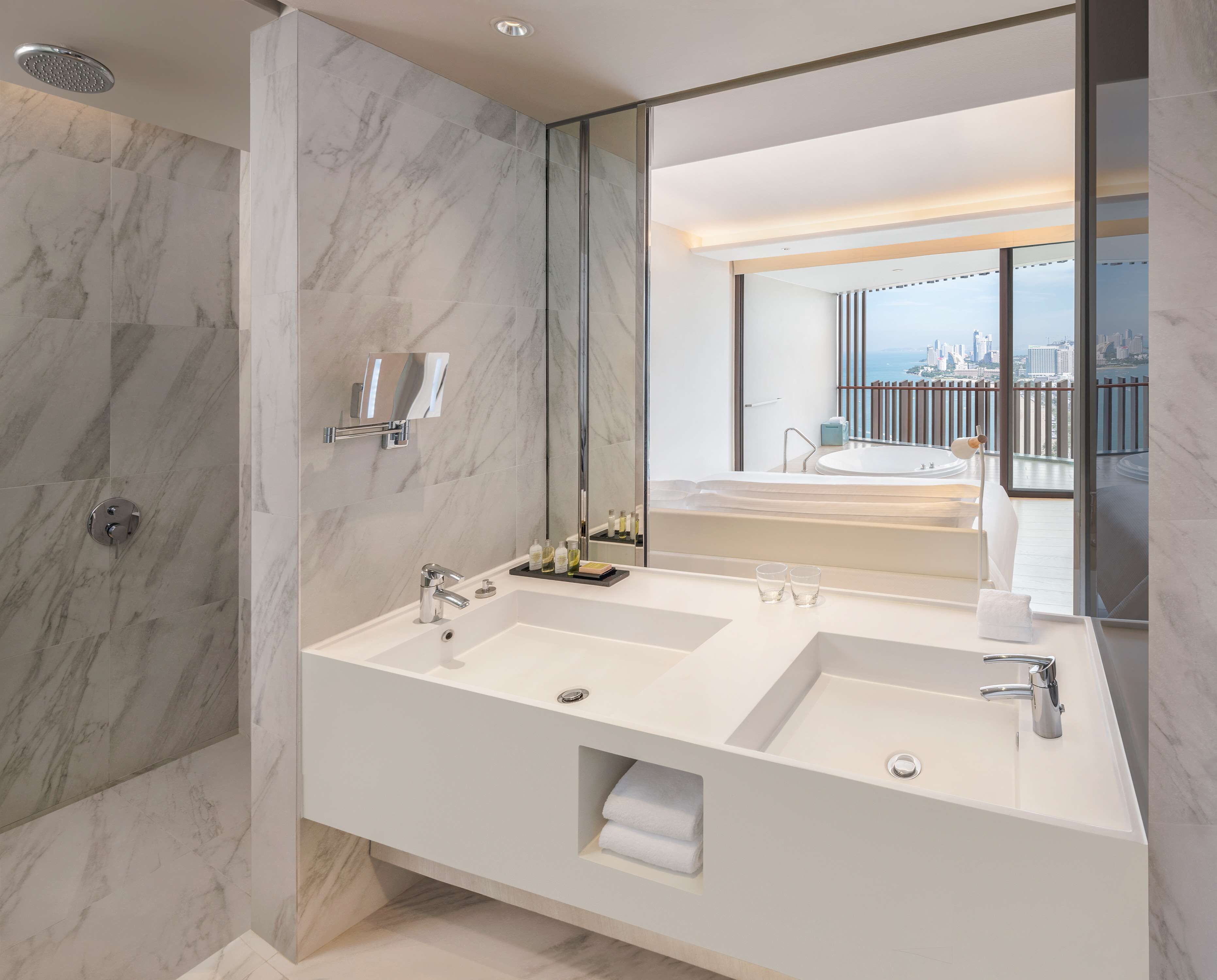 A modern bathroom with two sinks, a large mirror, and a shower.