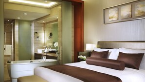 Habitación de hotel con una cama grande, baño independiente y vistas a la ciudad.