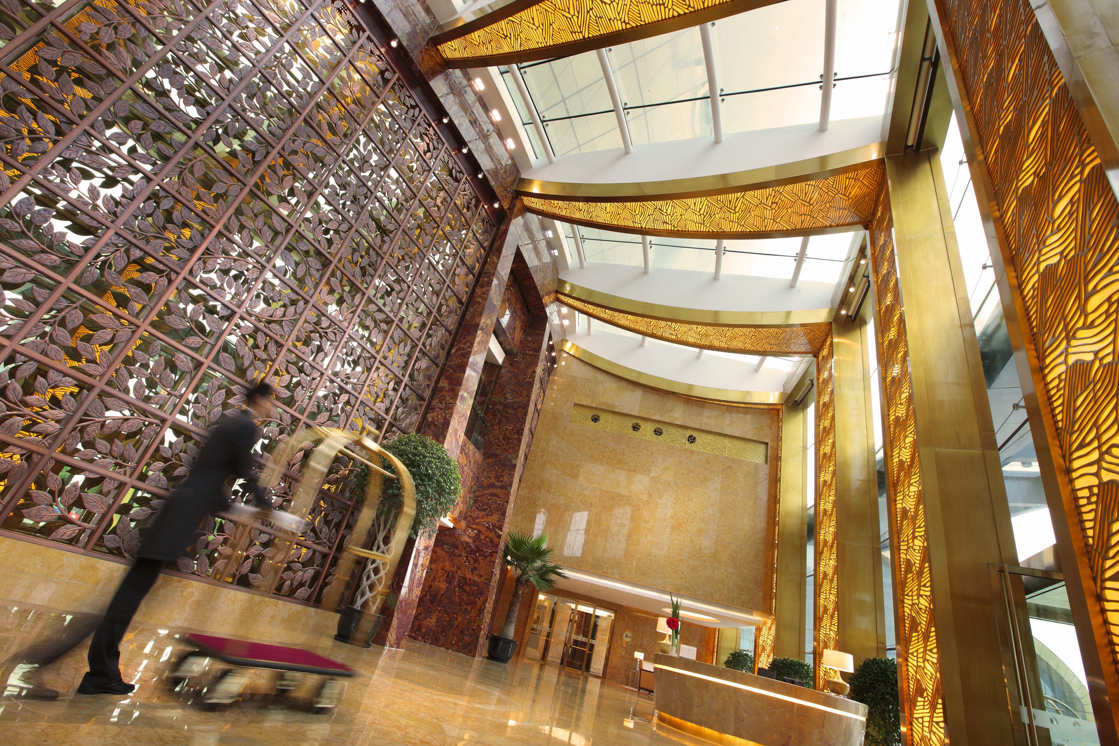 A spacious lobby with a high ceiling, a reception desk, and a decorative metal partition.