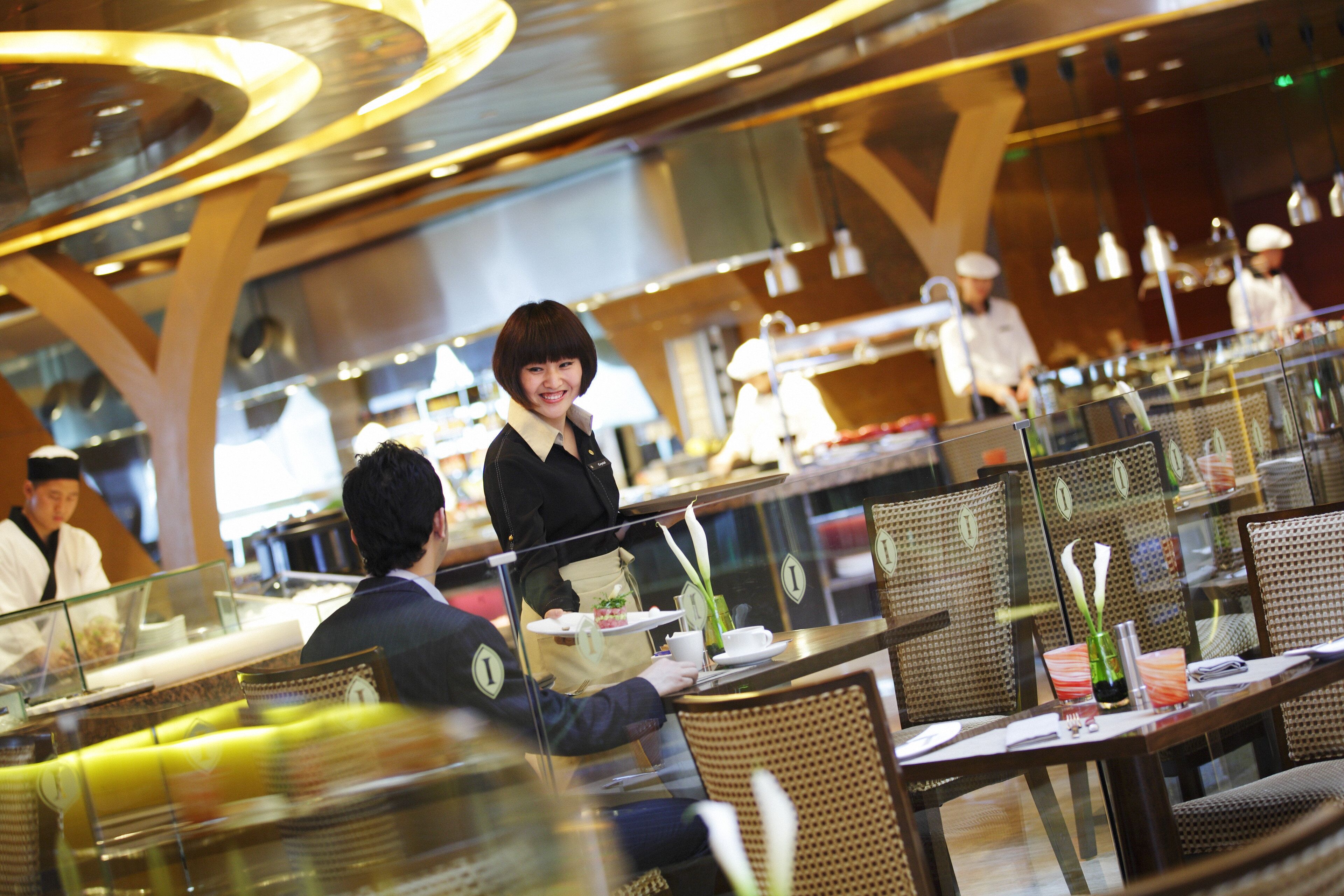 L'intérieur d'un restaurant avec des clients, du personnel de service et un espace buffet.