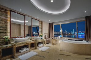 A modern bathroom with dual sinks, a large mirror, a bathtub, and a view of a cityscape at night. - InterContinental Hangzhou ICC by IHG (Hangzhou)