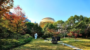 Un parque con un edificio moderno, senderos y árboles.