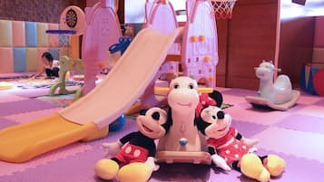 Ein Spielbereich für Kinder mit Rutsche, weichen Spielgeräten und Kuscheltieren.