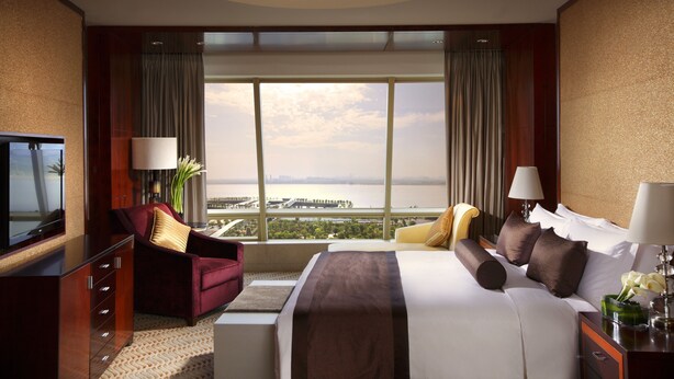 Habitación de hotel con una cama grande, televisión, escritorio y vista a la ciudad.