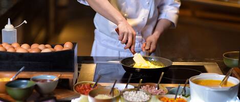 A chef preparing food in a kitchen with various ingredients and cooking utensils visible.