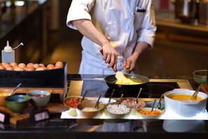 A chef preparing food in a kitchen with various ingredients and cooking utensils visible. - InterContinental Hangzhou ICC by IHG (Hangzhou)