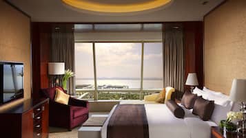 Habitación de hotel con una cama grande, televisión, escritorio y vista a un cuerpo de agua.