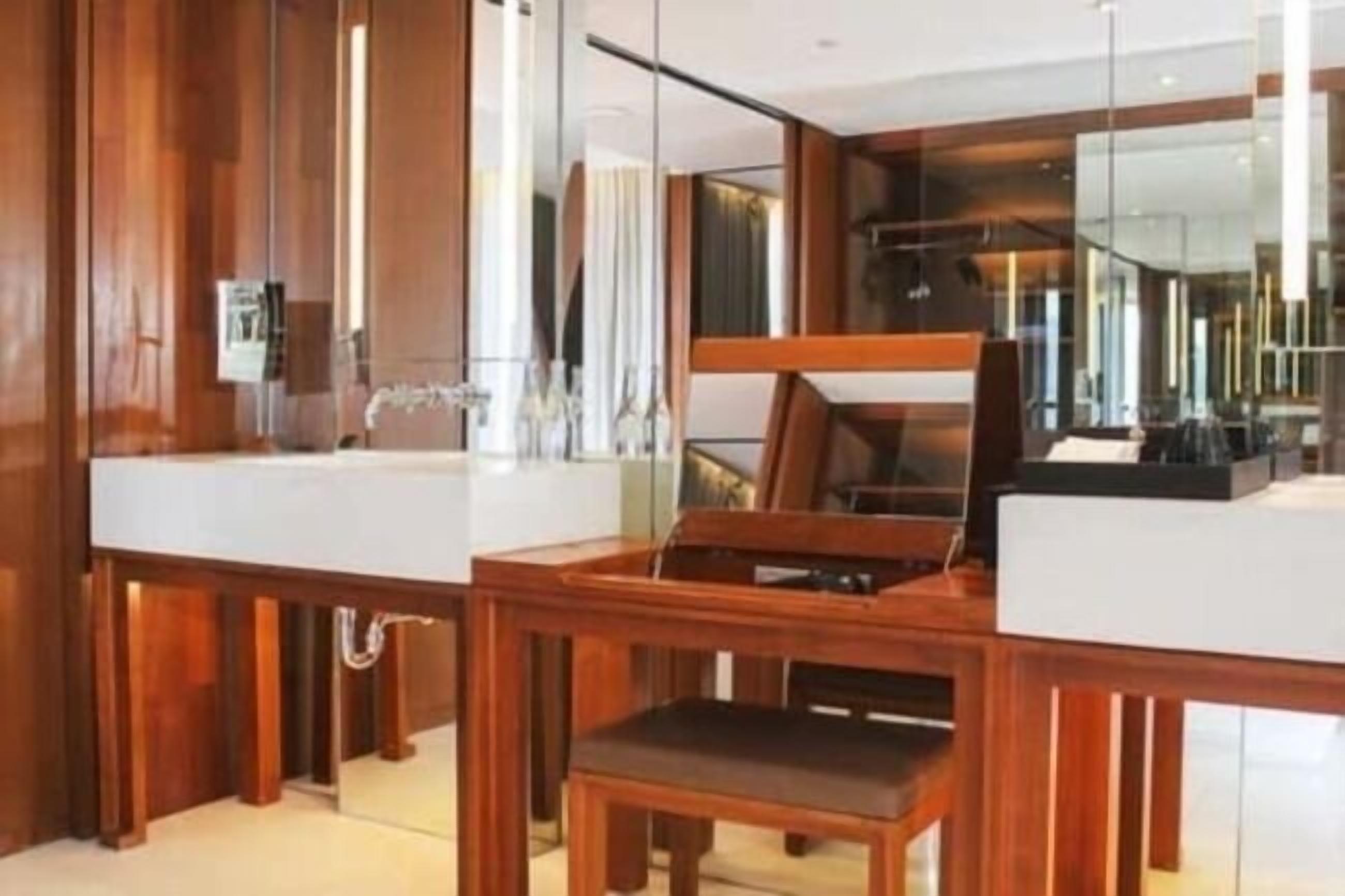 Un baño moderno con detalles de madera, un espejo grande y un tocador con lavabo.